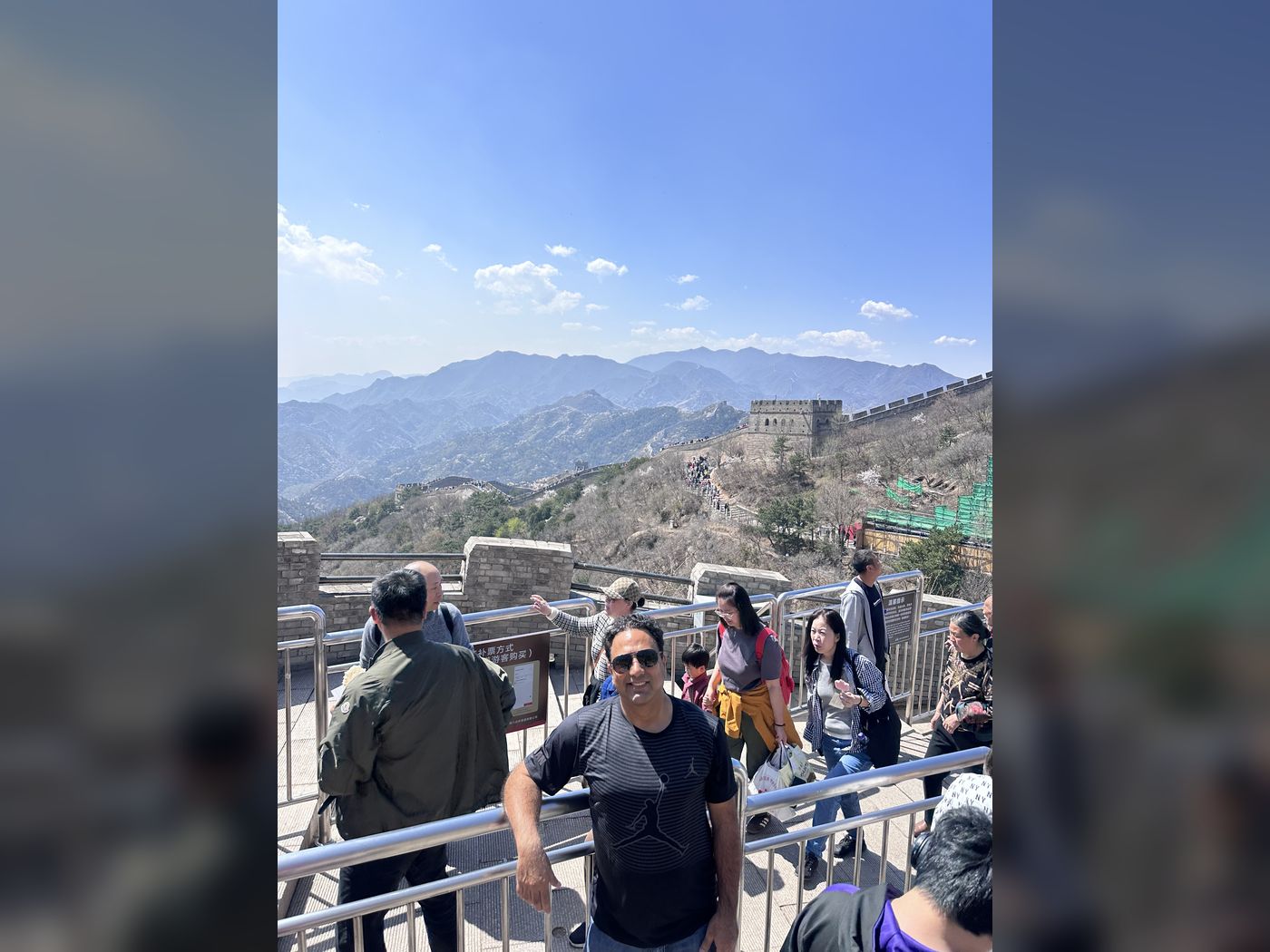 Saif Rehman on the Great Wall of China, with the wall crossing the mountains behind him